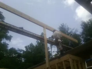 Carpenter setting a ridge beam over a new addition frame — Ice Dam Removal by Roofing Brothers in Rolesville