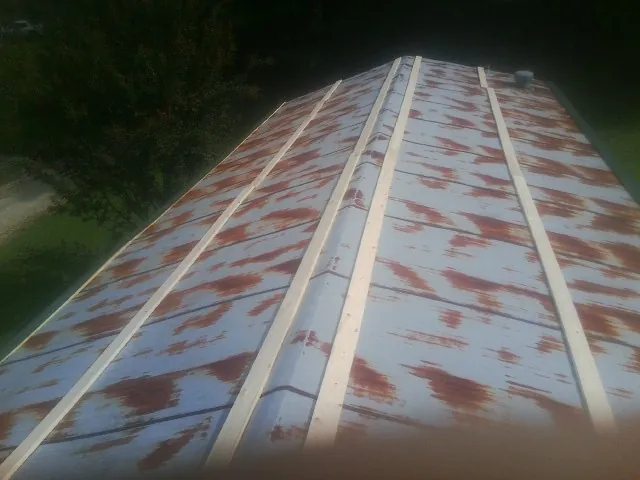 Rusted metal roof panels with new wood purlins before replacement in Rolesville