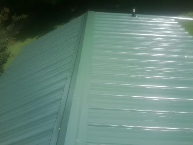 New green metal panels meeting at the ridge of a roof — Flat Roof Repair work by our crew in Rolesville