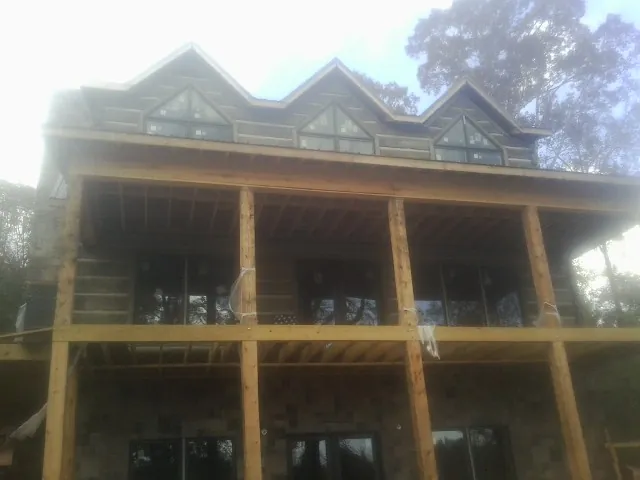 Dormers and porch framing on a large log home under construction — Roof Coating work by our crew in Rolesville