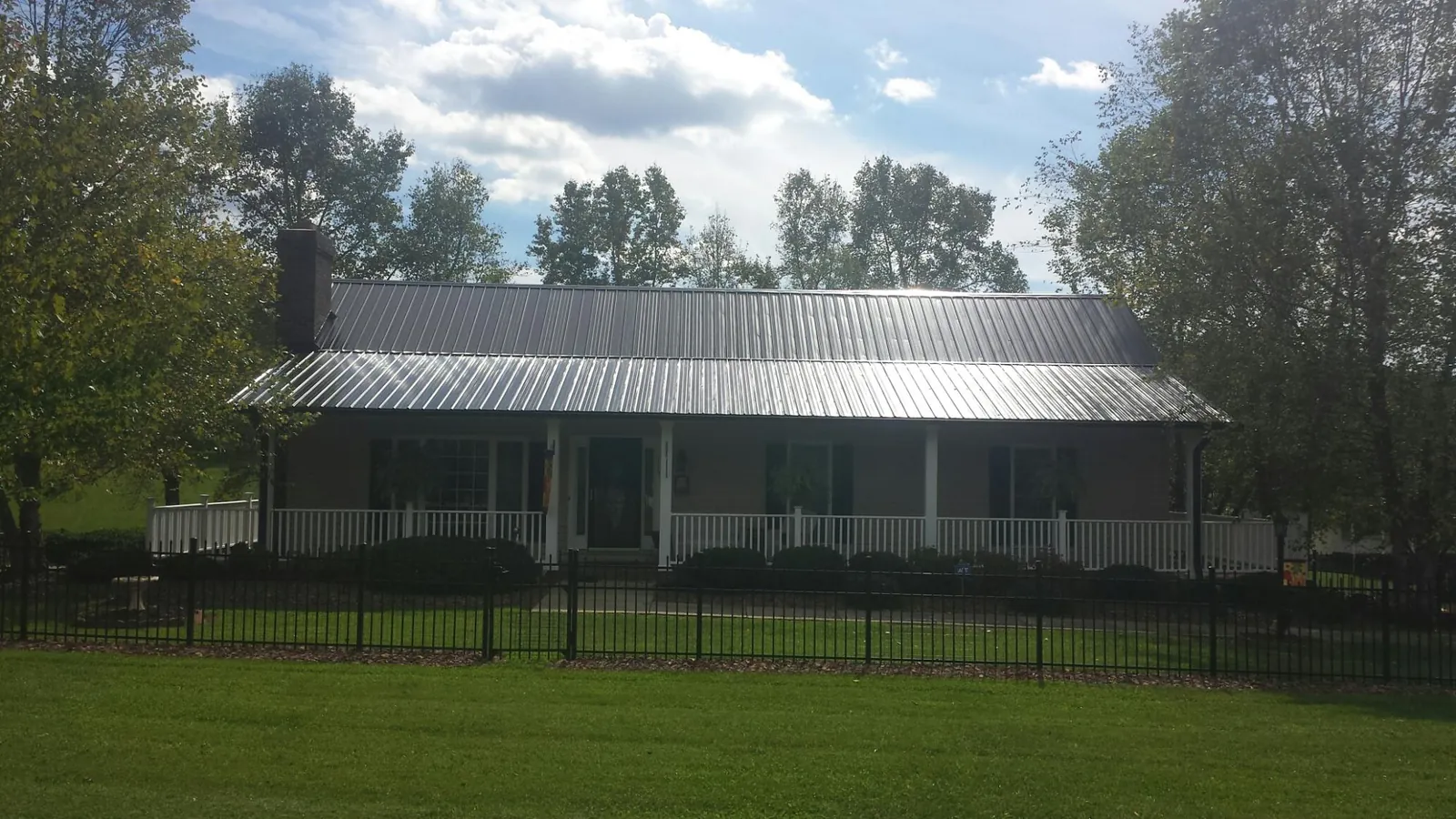 Gray metal roof on a brick ranch with a full width front porch — Gutter Guard Installation work by our crew in Rolesville