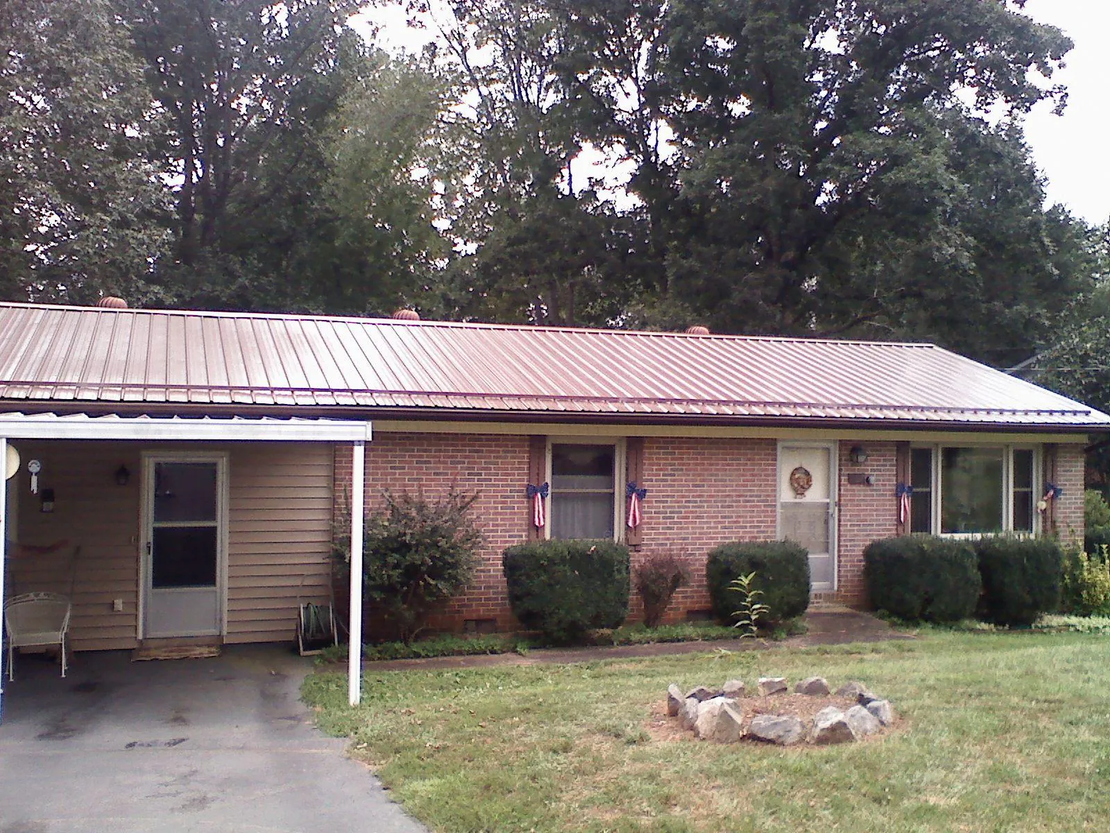 Bronze metal roof and carport on a brick ranch home — Roof Repair work by our crew in Rolesville