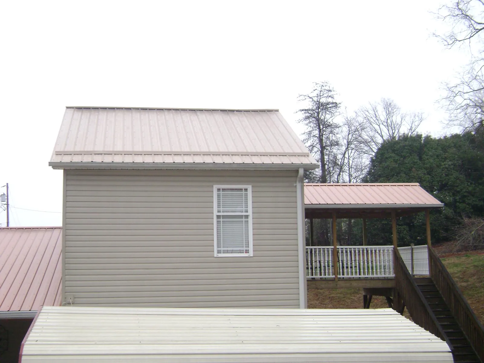 Tan metal roofs on a two story addition and attached porch, from a Roof Replacement job in Rolesville